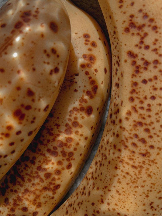 Close-up of ripe bananas with brown spots on peel, highlighting natural fruit texture